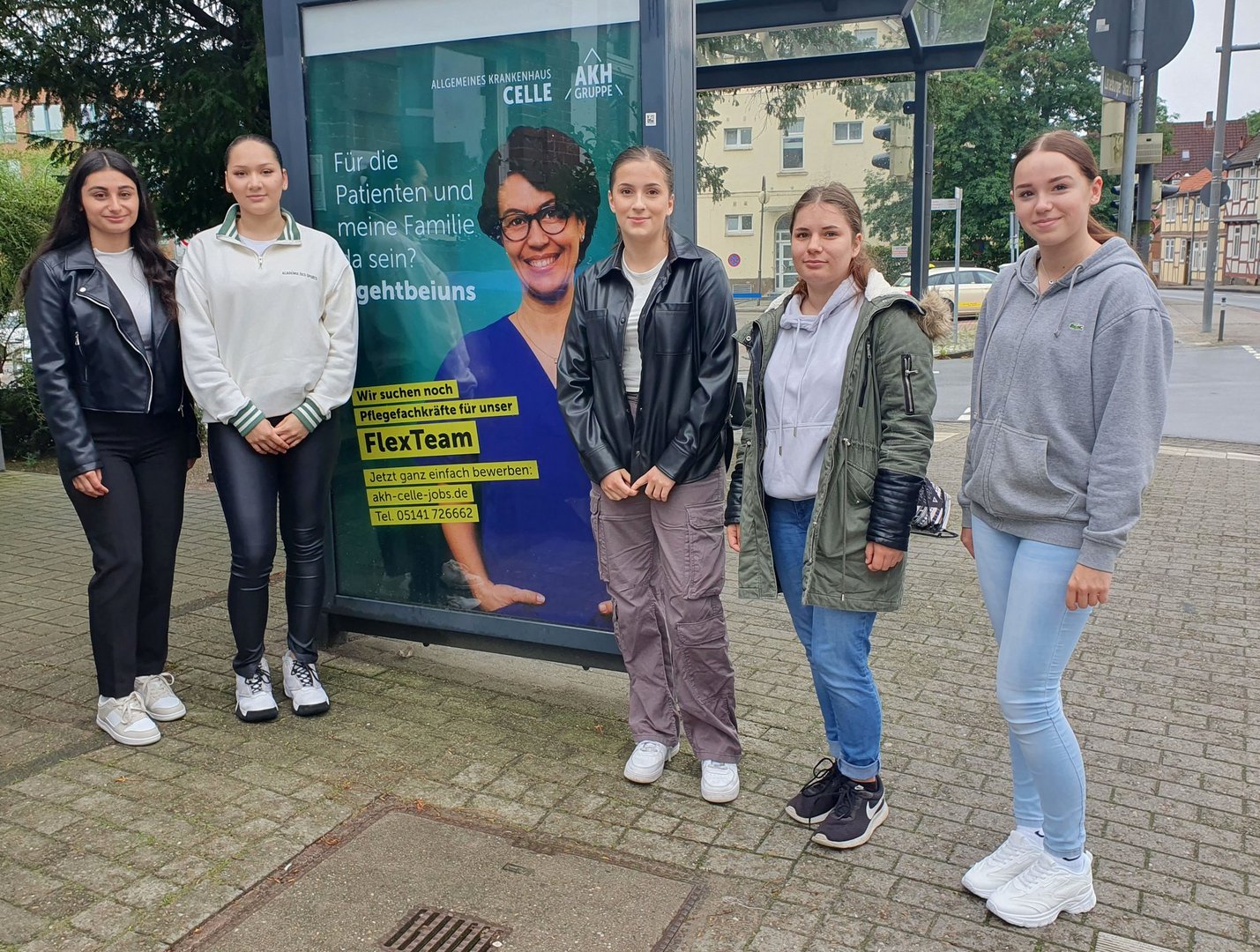 Gruppe junger Auszubildenden bei deren Start vor einem Plakat des AKH Celle.